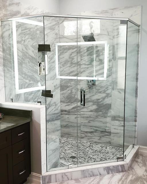 Lit vanity mirror above marble enclosure