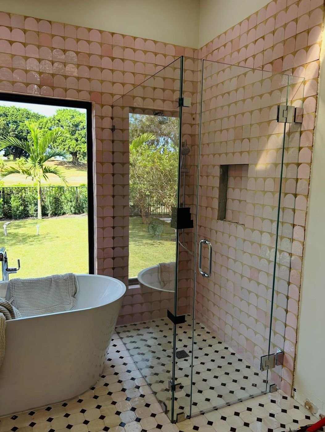 90-degree shower enclosure beside a freestanding tub and garden window