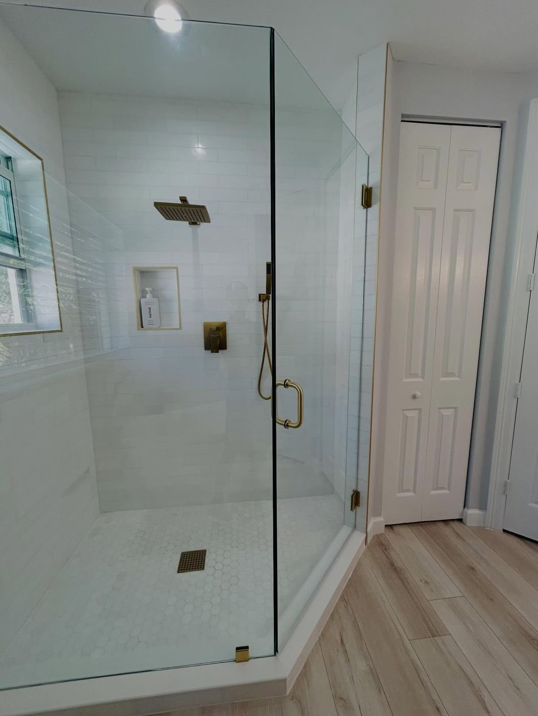 Frameless corner enclosure with brushed gold hardware